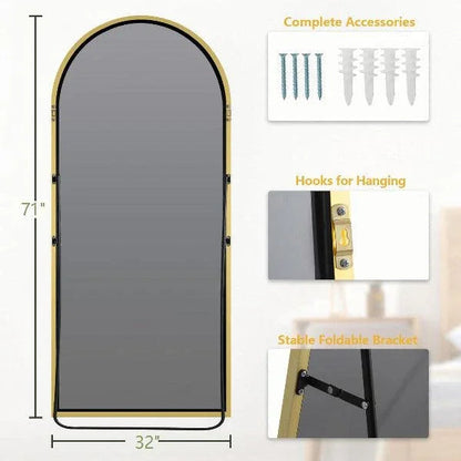 Gold arched floor mirror viewed at an angle against a plain background