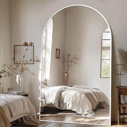 Oversized white arched floor mirror shown in a room setting