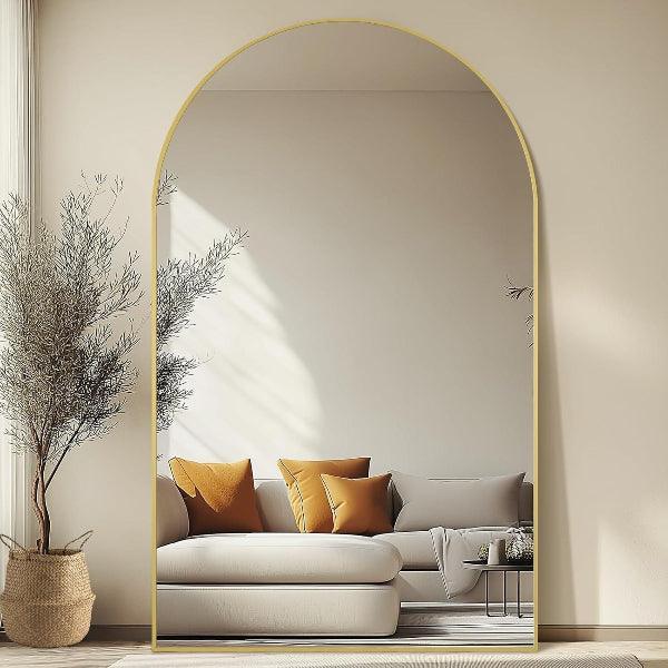 Gold arched mirror leaning against living room wall