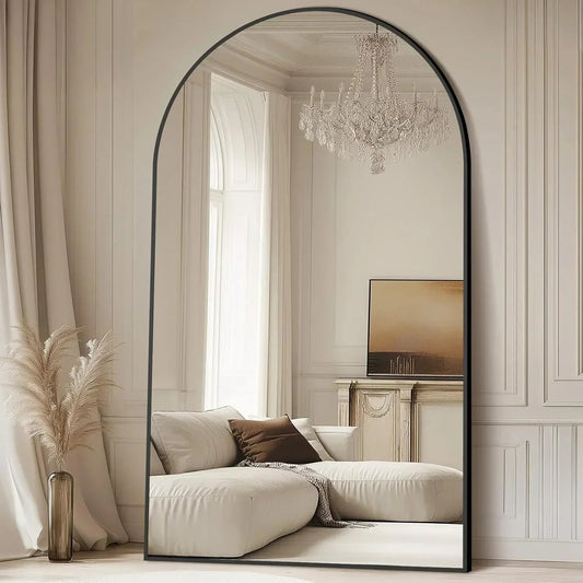 Oversized black arched floor mirror in a bedroom