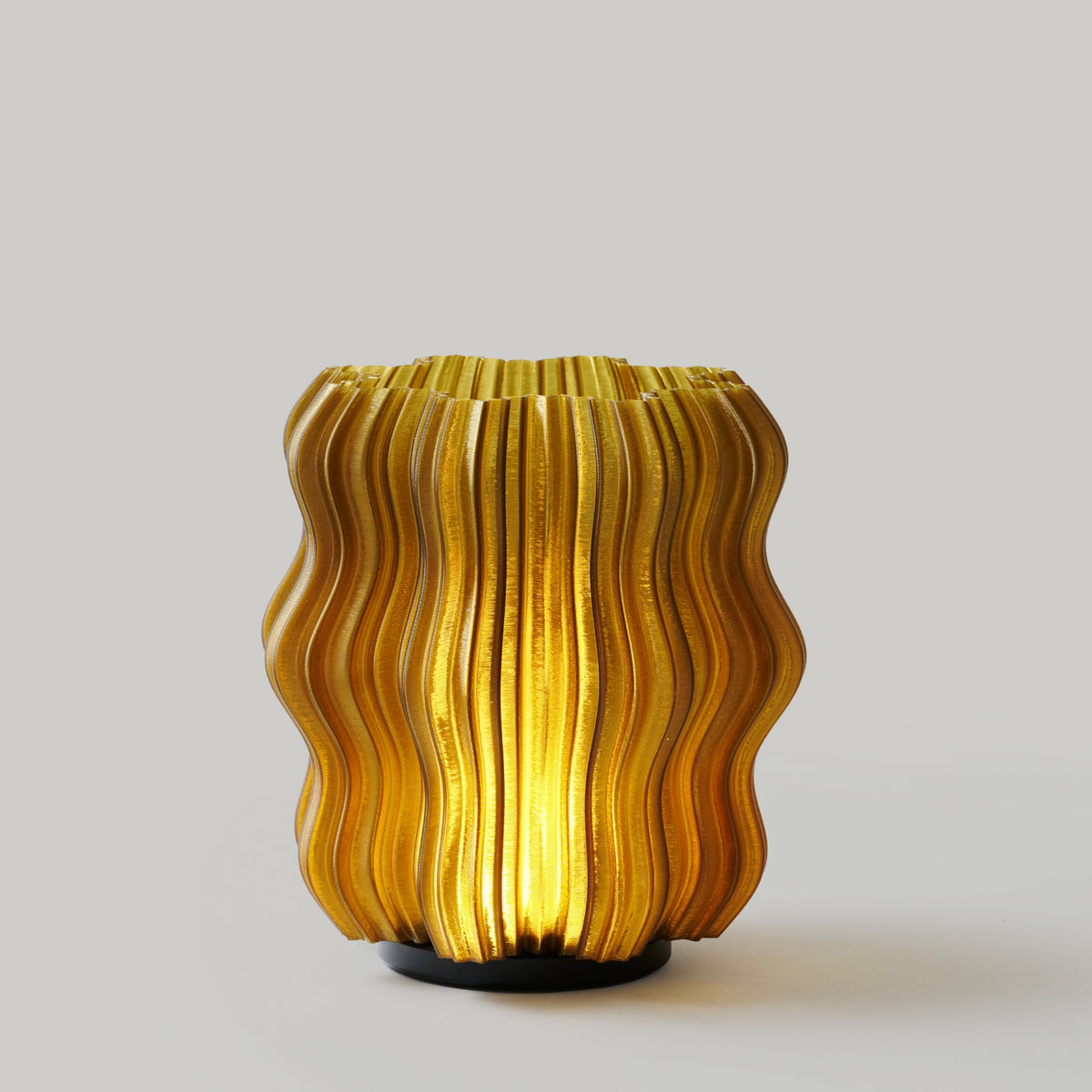 Cordless mini wavy table lamp with ribbed shade, glowing warm on a bedside table