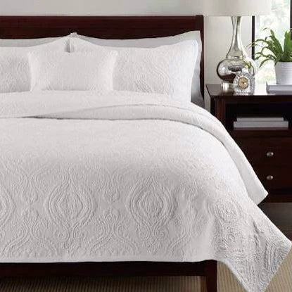 Embroidered quilted bedspread set styled on a bed with two pillowcases