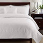 Embroidered quilted bedspread set styled on a bed with two pillowcases